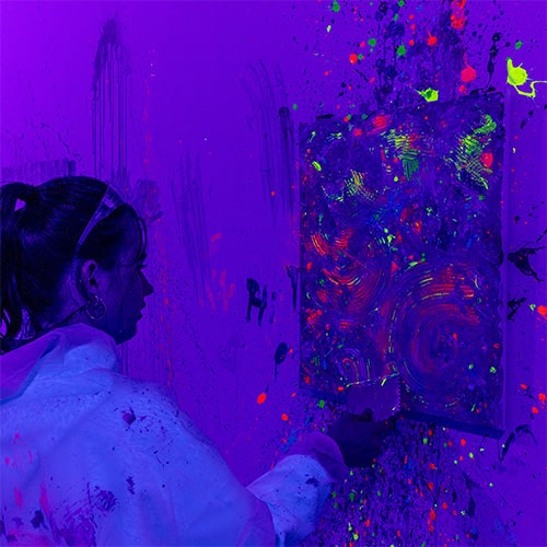 A woman using a pattern scraper on a canvas