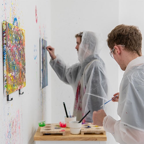 Two men painting a canvas